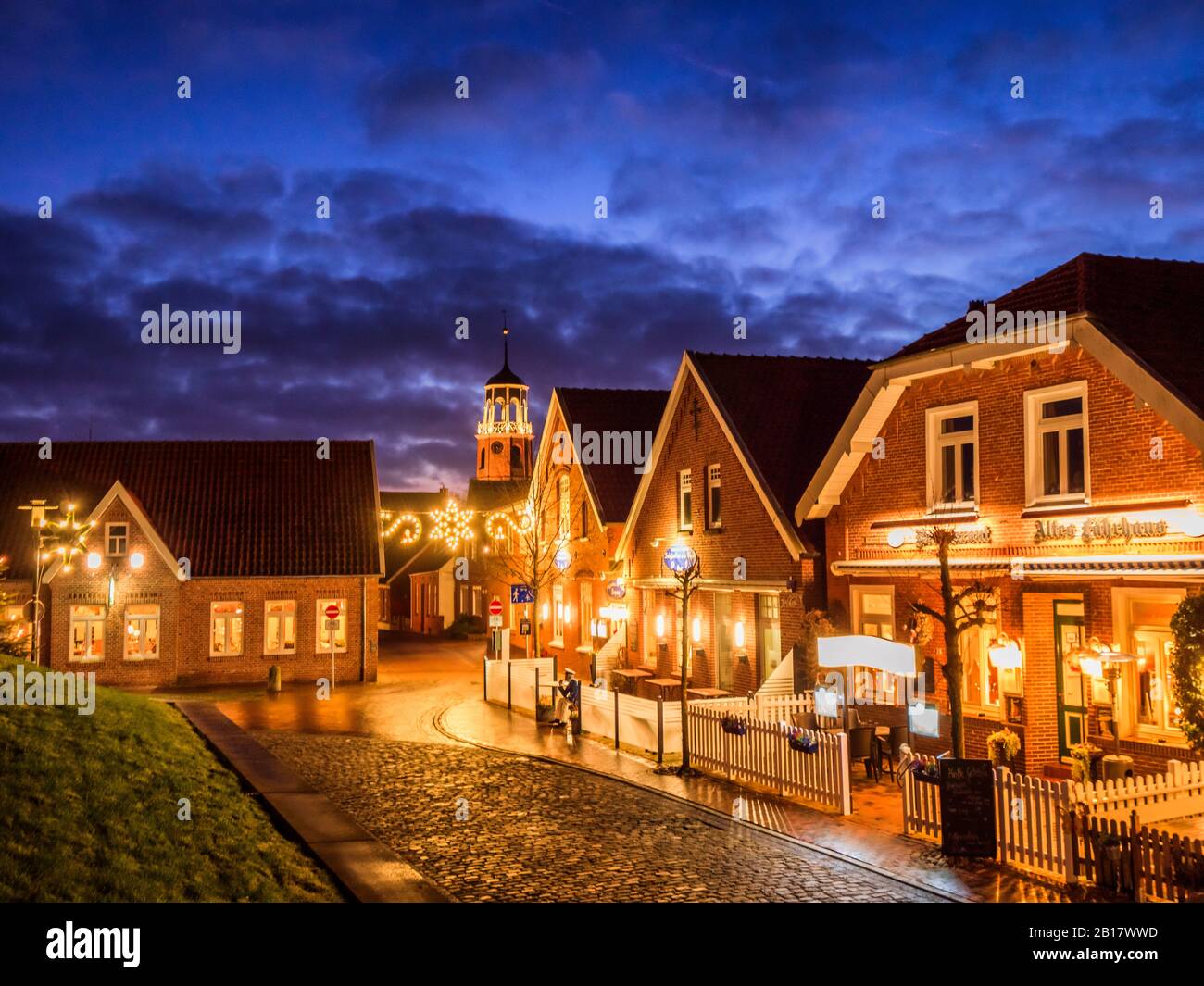 Deutschland, Niedersachsen, Landkreis leer, Friesland, Ditzum, Häuser beleuchtet für Weihnachten in der Dämmerung Stockfoto