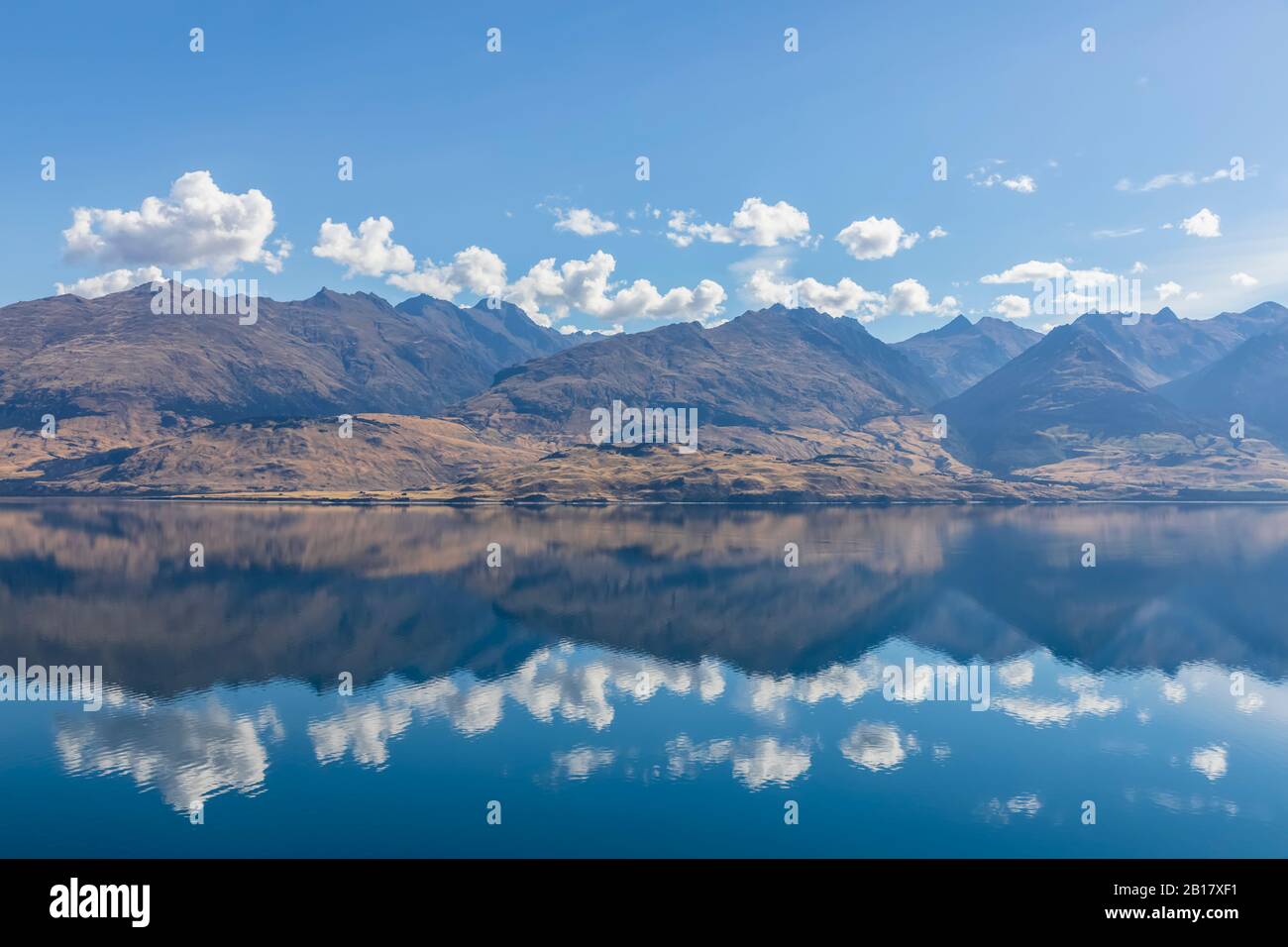 Neuseeland, Queenstown-Lakes District, Wanaka, Lake Wanaka, der den blauen Sommerhimmel und die umliegenden Hügel widerspiegelt Stockfoto