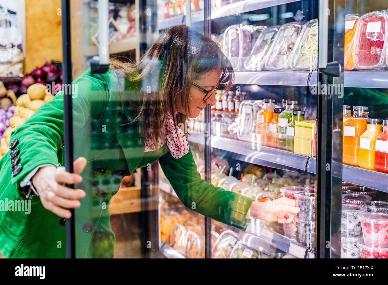 Frau, die verpackte Beeren aus dem Kühlregal in Bio-Shop Stockfoto