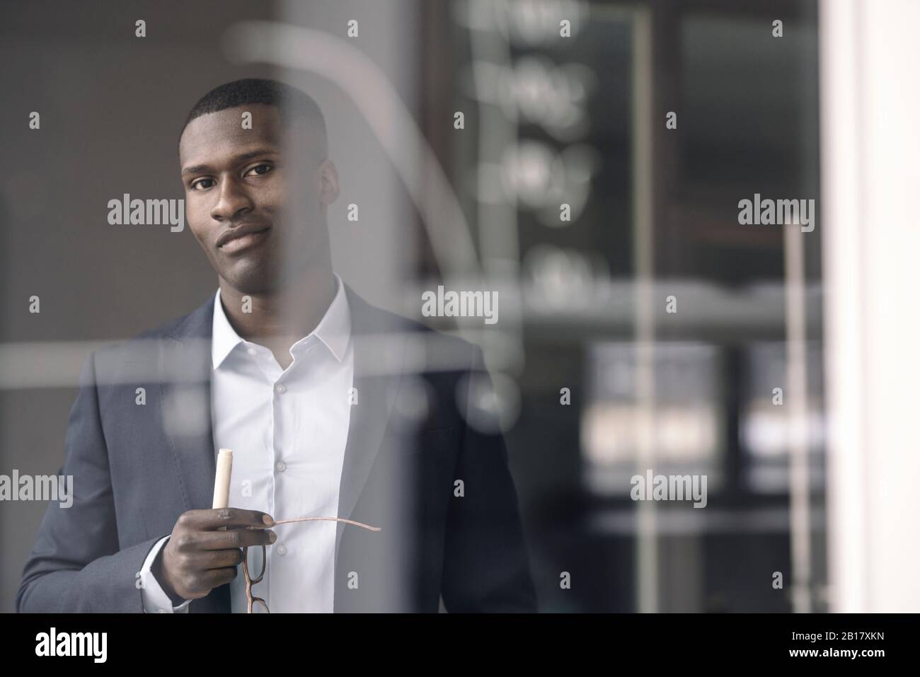 Porträt eines lächelnden jungen Geschäftsmannes hinter dem Diagramm auf der Glasscheibe im Büro Stockfoto