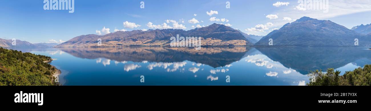 Neuseeland, Queenstown-Lakes District, Wanaka, Lake Wanaka, der den blauen Sommerhimmel und die umliegenden Hügel widerspiegelt Stockfoto