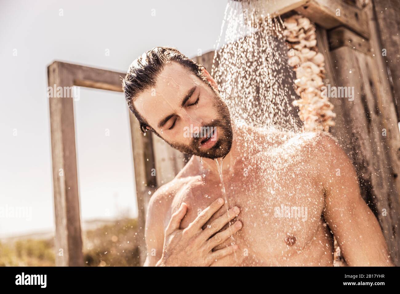 Junger Mann unter einer Dusche im Freien Stockfoto