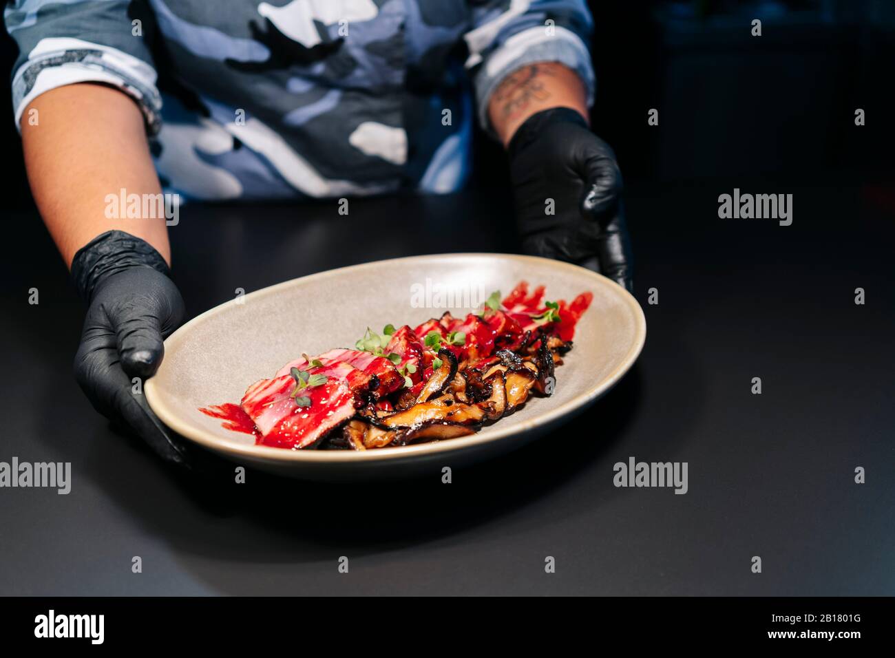Der Koch zeigt ein zubereitetes Gericht auf dem Tisch in der Restaurantküche Stockfoto