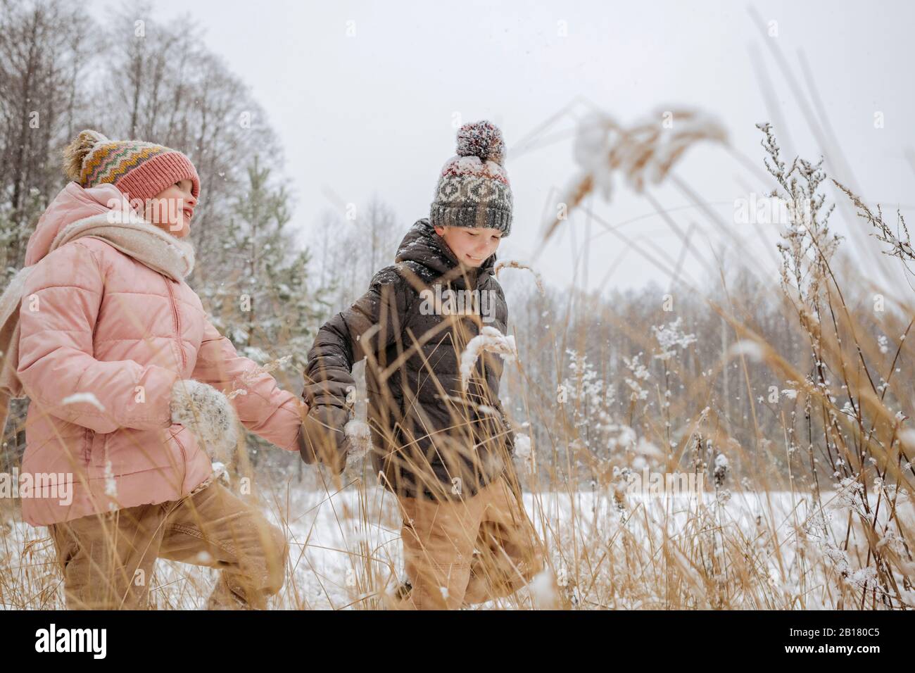 Zwei Geschwister gehen im Winterwald Hand in Hand Stockfoto