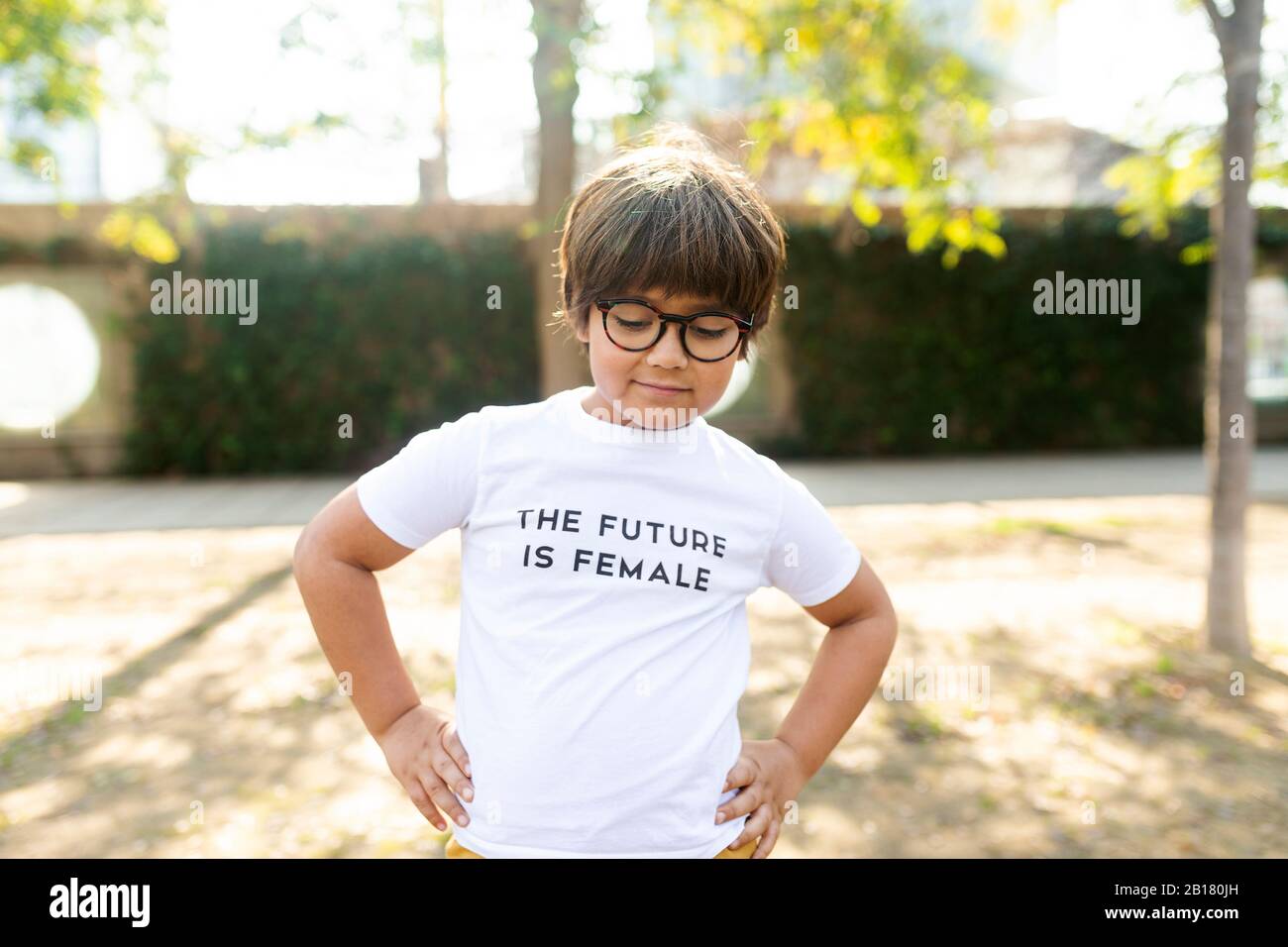 Stolzer kleiner Junge, der auf der Straße mit Aufdruck auf dem T-Shirt steht und sagt, die Zukunft sei weiblich Stockfoto