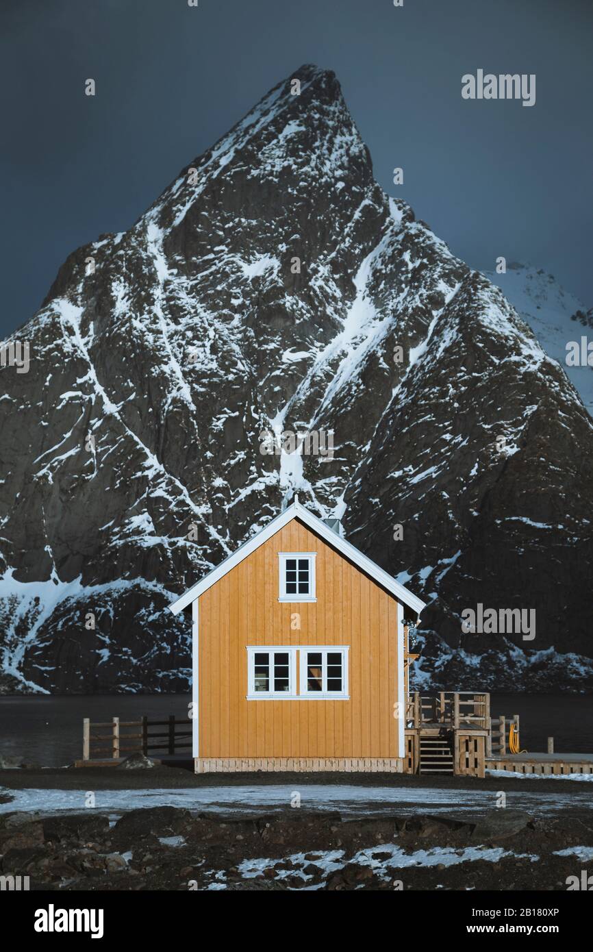 Norwegen, Moskenes, Lofoten Inseln, Sakrisoy, traditionelle Rorbu Fischerhütte mit Olstinden Gipfel im Hintergrund Stockfoto