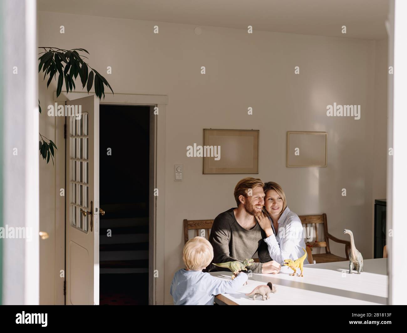 Entspannte Familie mit Dinosaurier-Figuren zu Hause am Tisch sitzen Stockfoto