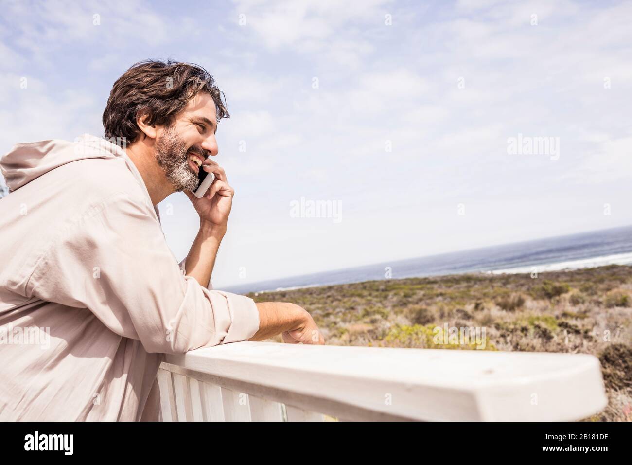 Mann im Bademantel und telefonieren mit Smartphone auf der Terrasse Stockfoto
