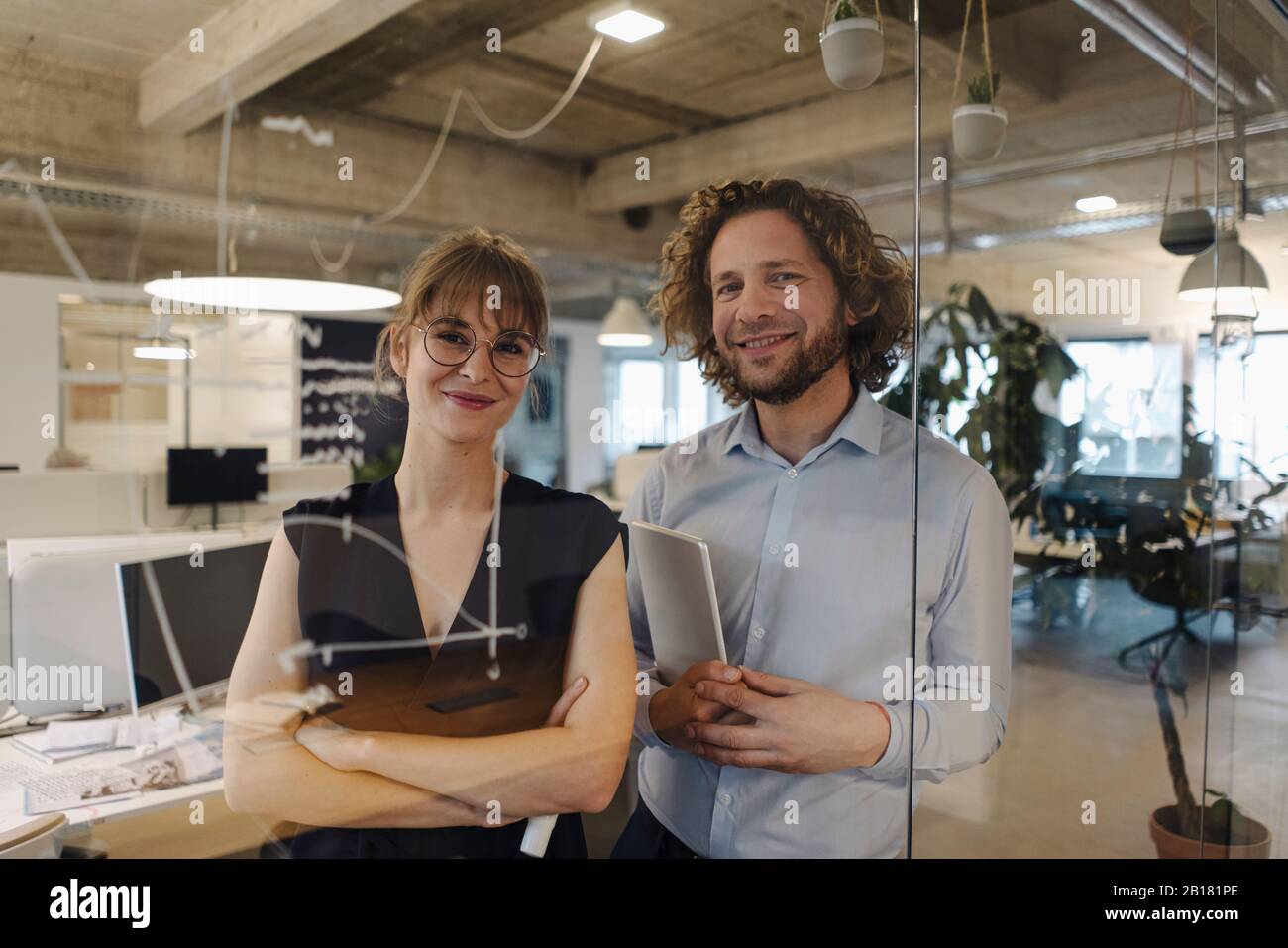 Porträt eines selbstbewussten Geschäftsmannes und Geschäftsfrau hinter der Glasscheibe im Büro Stockfoto