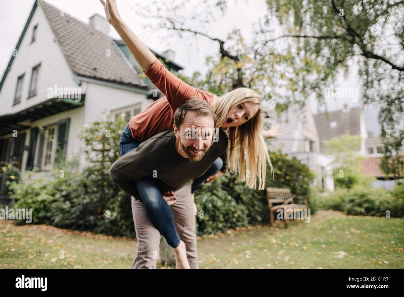 Jubelnde Paare, die vorgeben zu fliegen und in ihrem Garten stehen Stockfoto