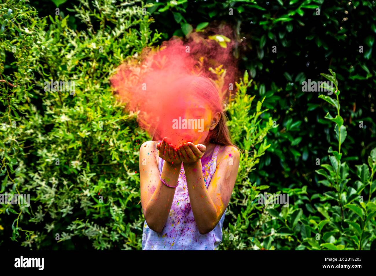 Mädchen bläst rote Pulverfarbe in der Natur Stockfoto