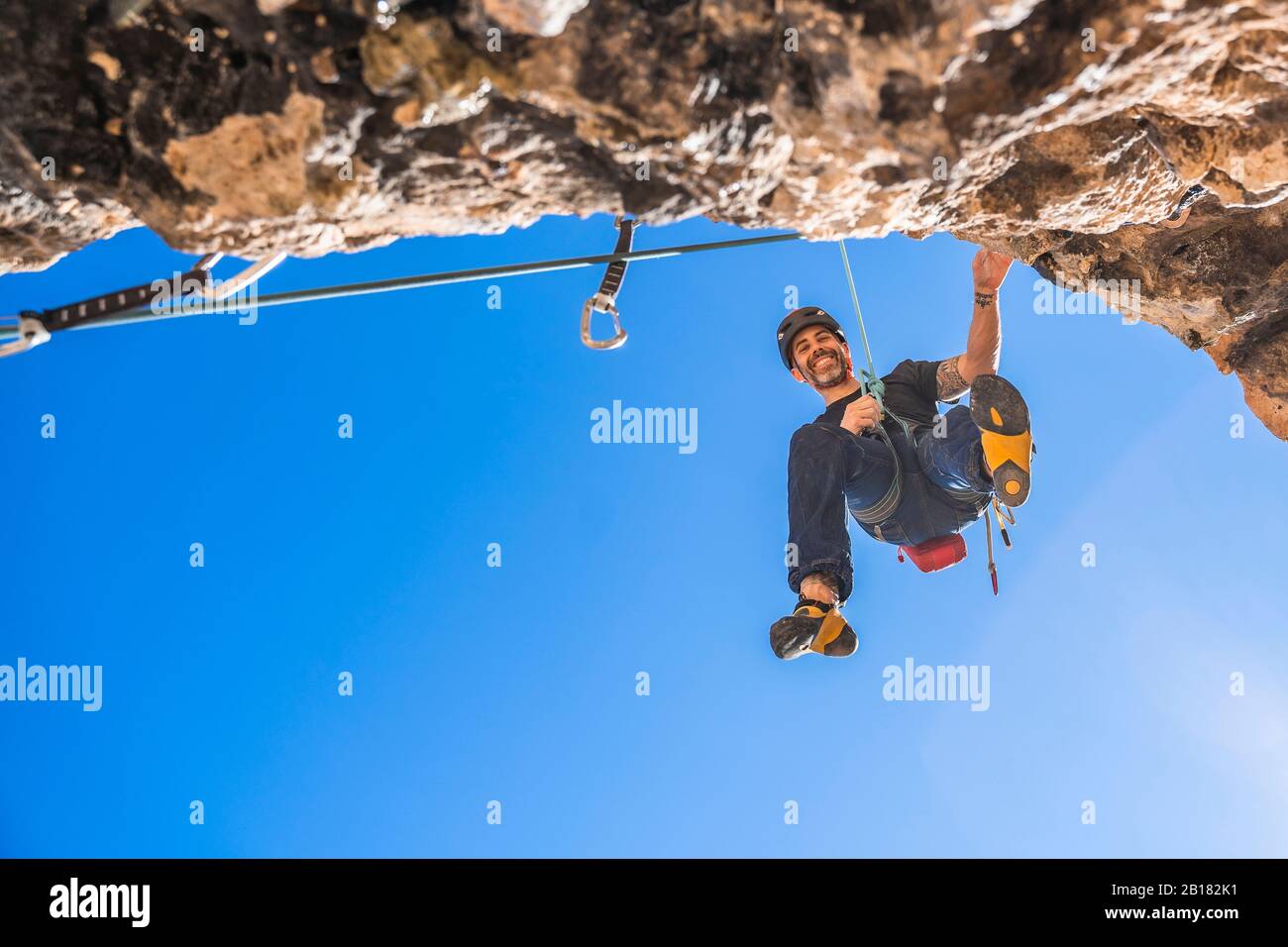 Porträt eines lächelnden Kletterers, der sich von der Felswand abseilen kann Stockfoto