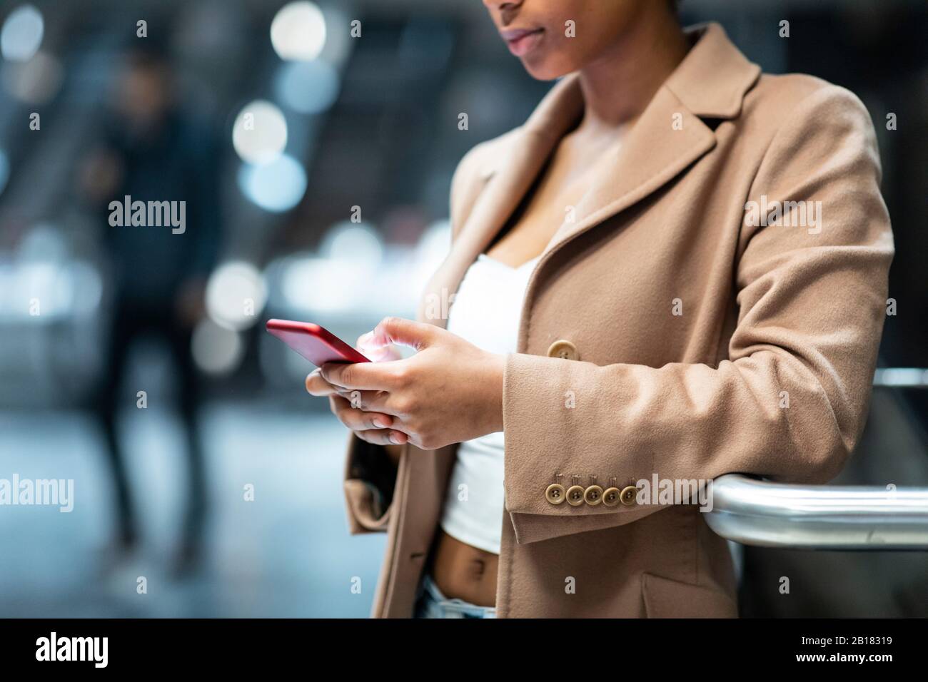Nahaufnahme einer jungen Frau, die in der U-Bahn-Station Handy benutzt Stockfoto