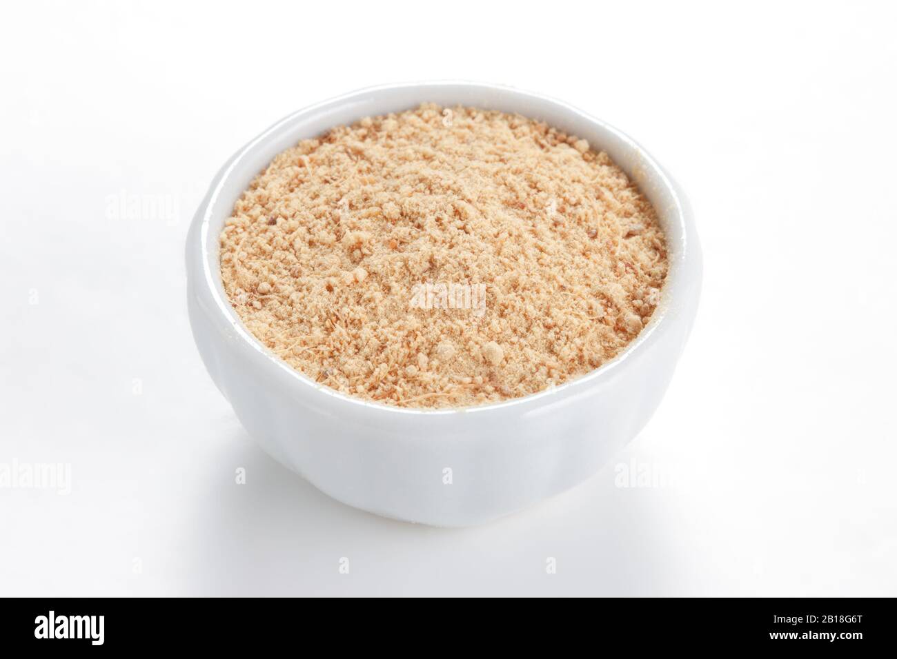 Gemahlener Ginger (Zingiber officinale) in einer weißen Schüssel auf weißem Grund. Wird weltweit als Delikatesse, Medizin oder Gewürz verwendet. Stockfoto
