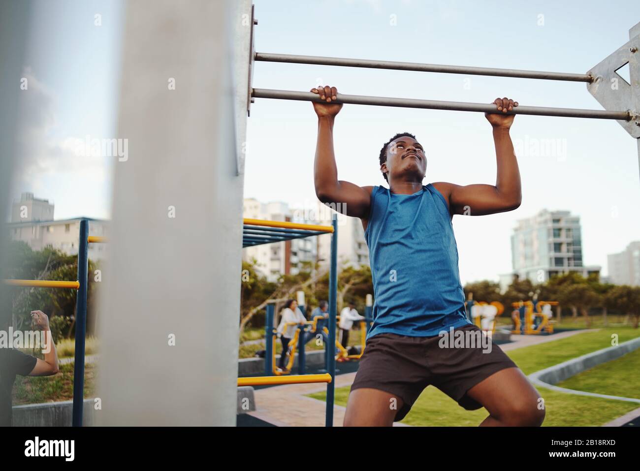 Vorderansicht eines starken afroamerikanischen männlichen Athleten, der an der horizontalen Bar im öffentlichen Fitnesspark aufzieht Stockfoto