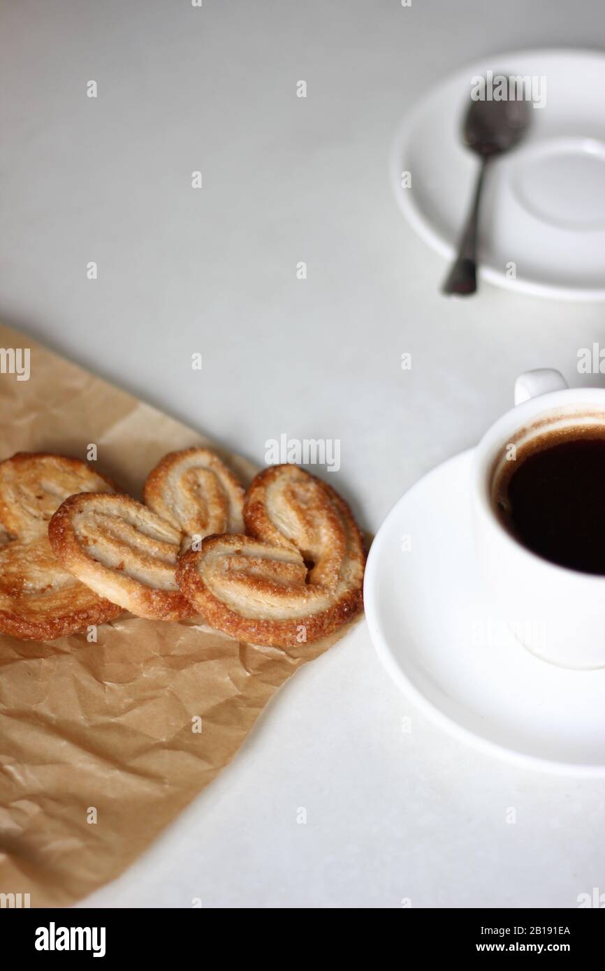 Frisch Gebackene Palmiers Plätzchen auf Pergamentpapier mit einer Tasse Espresso. Frühstücksgebäck. Stockfoto