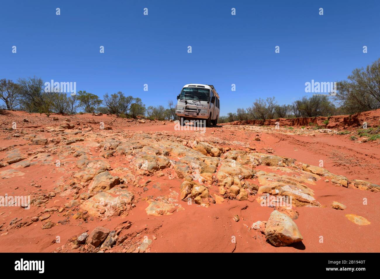 Geländewagen Toyota Coaster mit Geländewagen auf einer roten Straße im australischen Outback in der Nähe von Alice Springs, Northern Territory, NT, Australien Stockfoto