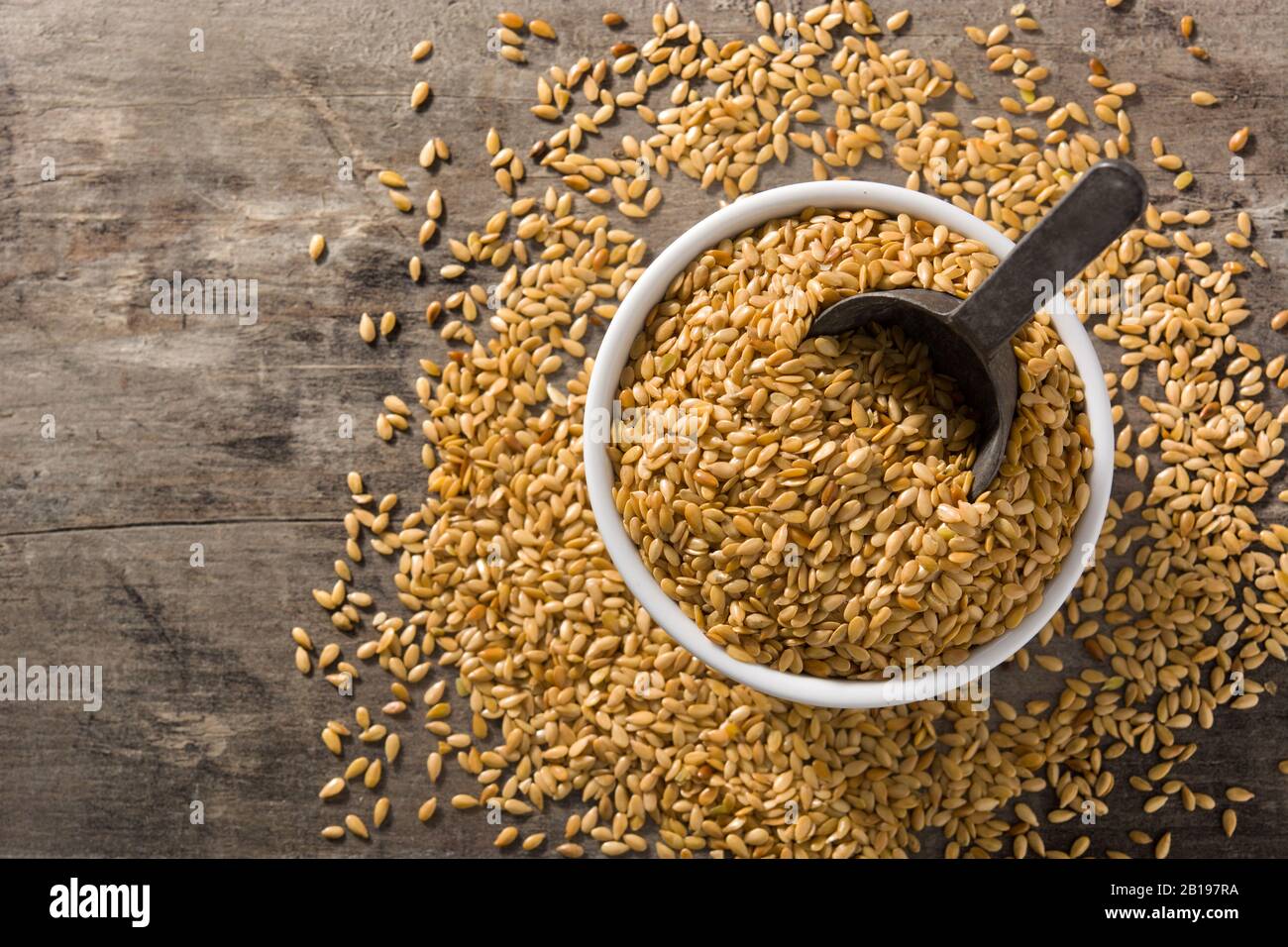 Goldene Flachssamen in weißer Schleife auf Holztisch. Draufsicht. Kopierbereich Stockfoto