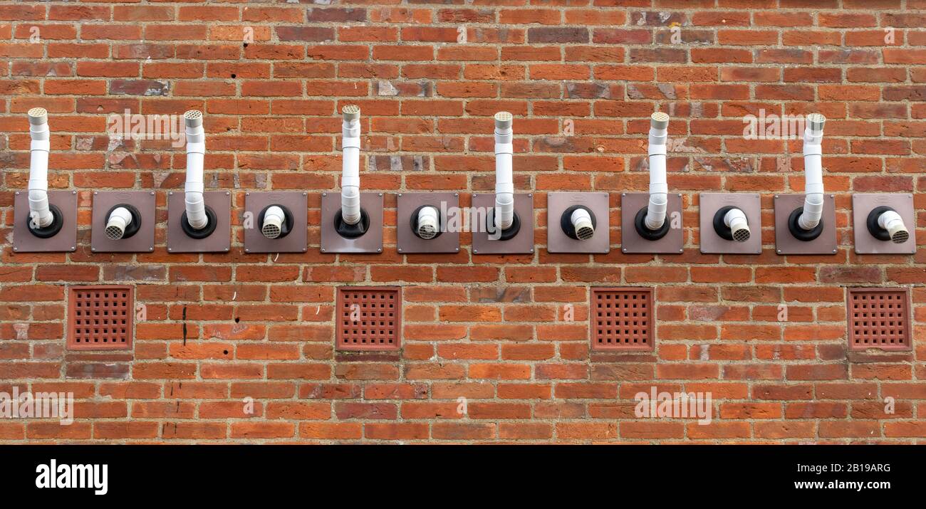 Wechsellufteinlass- und Abluftöffnungen oder Rohre für Kessel oder Ofen an der Außenwand eines Gebäudes Stockfoto