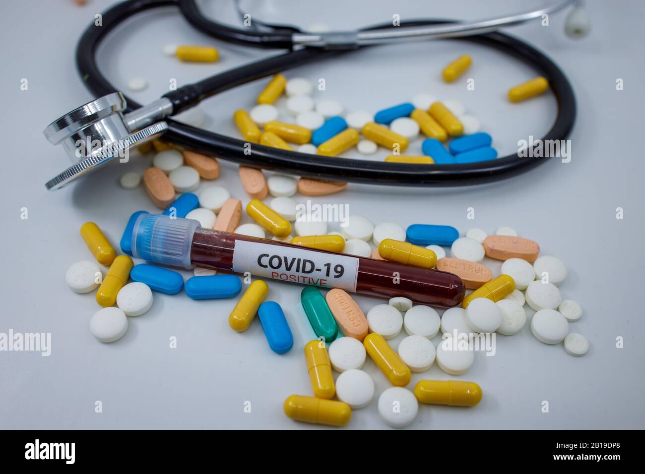Blut-Reagenzglas für das neue, sich schnell ausbreitende Coronavirus, das seinen Ursprung in Wuhan, China, auf einem großen Haufen verschiedener Pillen hat Stockfoto