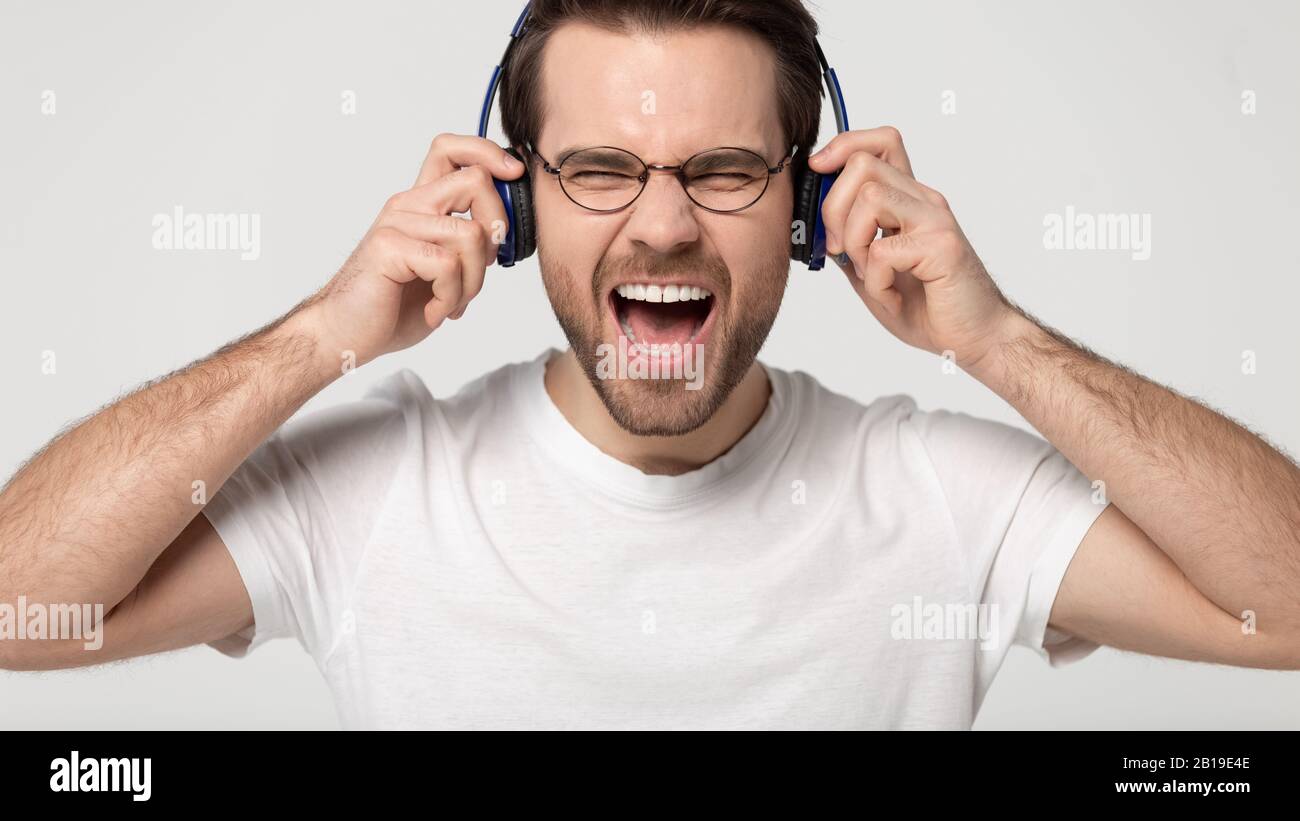 Headshot Studio Portrait überglücklich junger Mann mit kabellosen Kopfhörern. Stockfoto