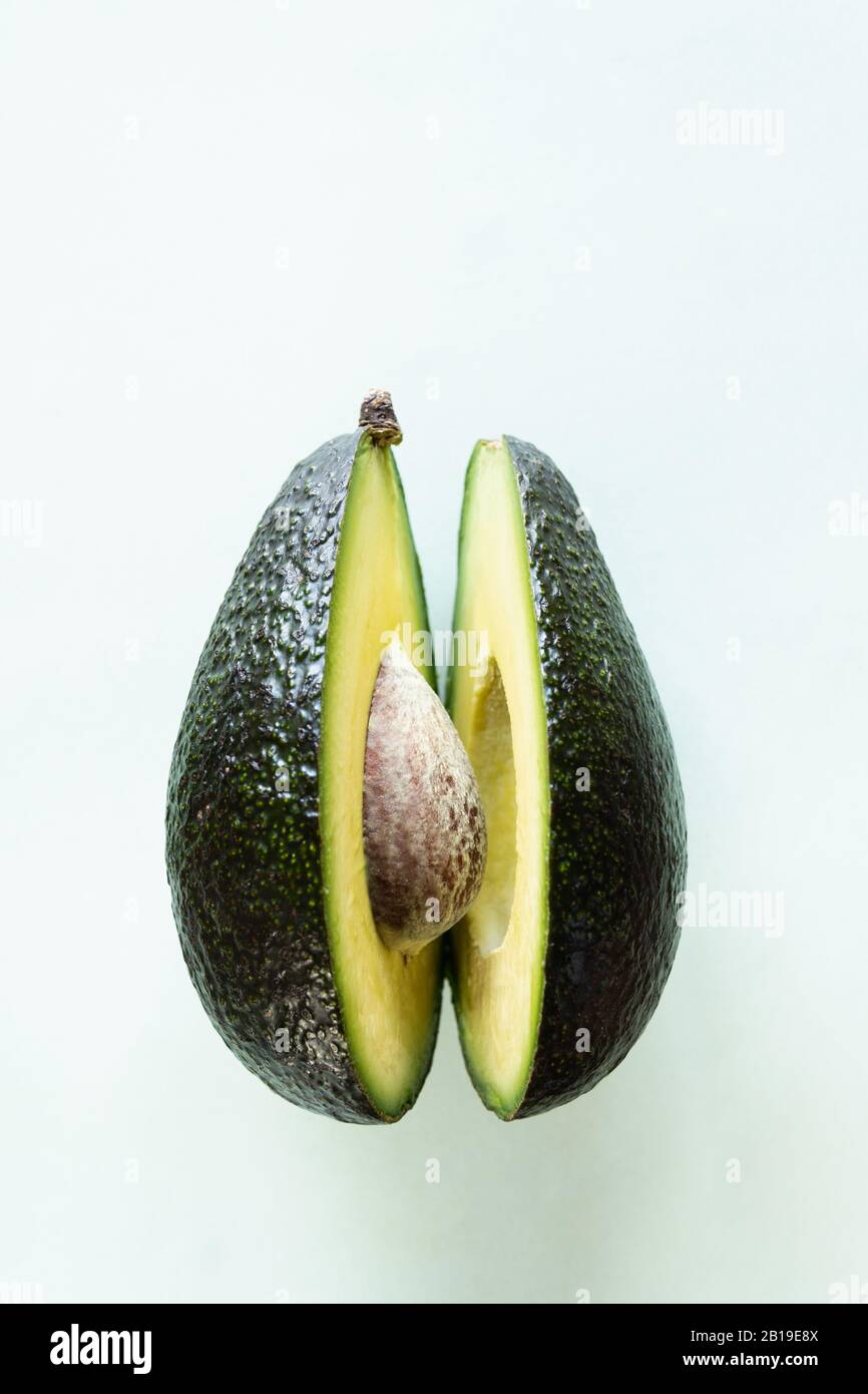 Bereit zum Essen Avocado in zwei Hälften geschnitten, isoliert auf hellgrünem Hintergrund. Stockfoto
