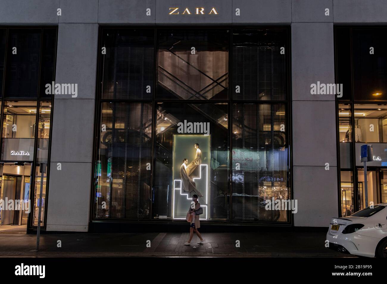 Ein Fußgänger, der eine Gesichtsmaske trägt, läuft am Zara-Markenladen und dem Logo in Hongkong vorbei.Das tödliche Coronavirus (COVID-19) hat die meisten Industrien, Fabriken und Einkaufszentren in China zum Stillstand gebracht. Mehr als 50 Millionen Menschen unter Quarantäne. Länder beschränken sich auf Einträge, um die Verbreitung des Virus zu kontrollieren. Sowie mehr als 25.000 Flugausfälle weltweit. Viele Länder können keinen Rohstoff aus China holen. Lange Zeit abhängig von den Ausgaben der chinesischen Käufer erinnern nach Hause. Der Luxusgüterkonzern Herms wird Investoren am Mittwoch, 26. Februar 2019 eine Aktualisierung zur Verfügung stellen. Analysten haben warne Stockfoto