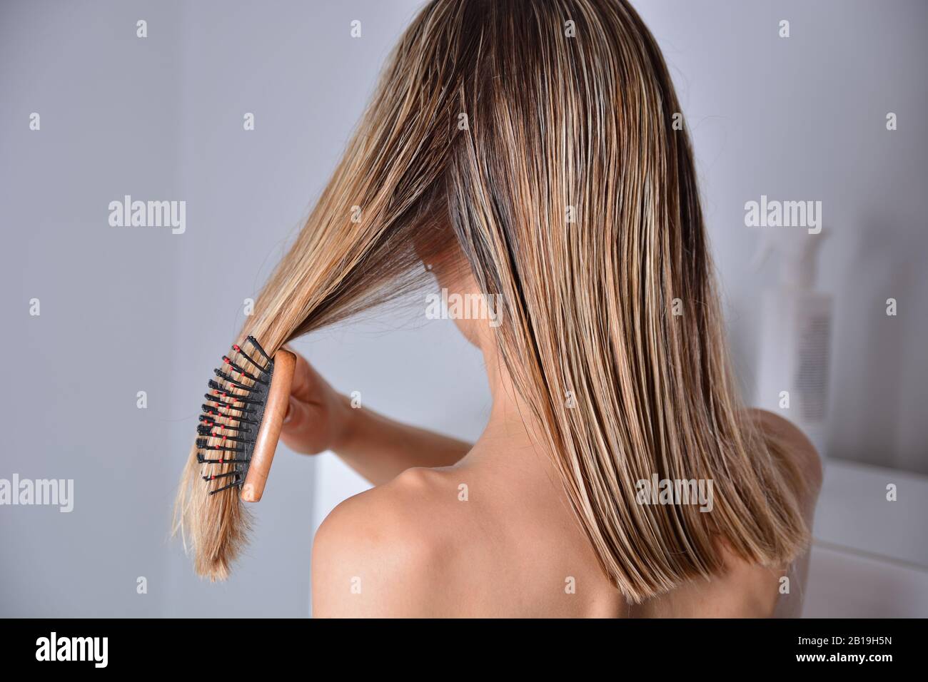 Attraktives Mädchen mit Kammaufsatz, das nach dem Duschen zu Hause ihr nasses blondes Haar putzt. Sorgt für gesundes und sauberes Haar. Beauty-Salon-Konzept. Nahaufnahme Stockfoto
