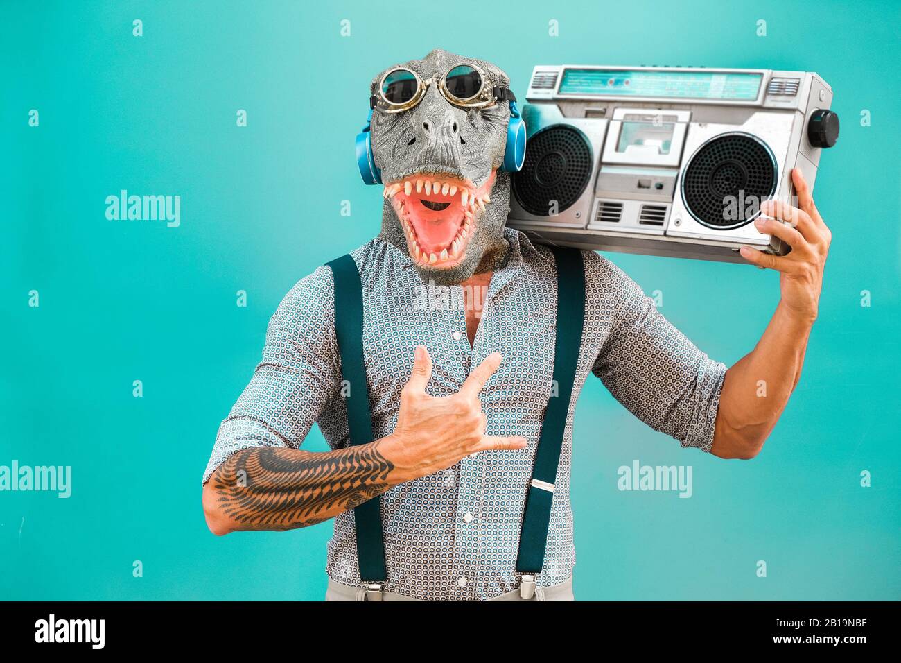 Verrückter Senior tanzt Rockmusik mit t-rex-maske - Tattoo trendiger Kerl mit Spaß Musik mit Boombox-Stereo - Absurder und lustiger Trend-Con Stockfoto