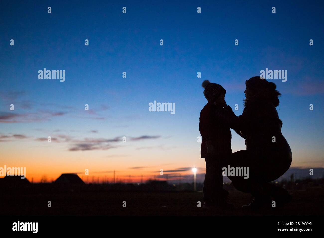 Mutter kümmert sich um ihr Baby. Mutter und ihre kleine Tochter laufen am frostigen Abend draußen. Stockfoto