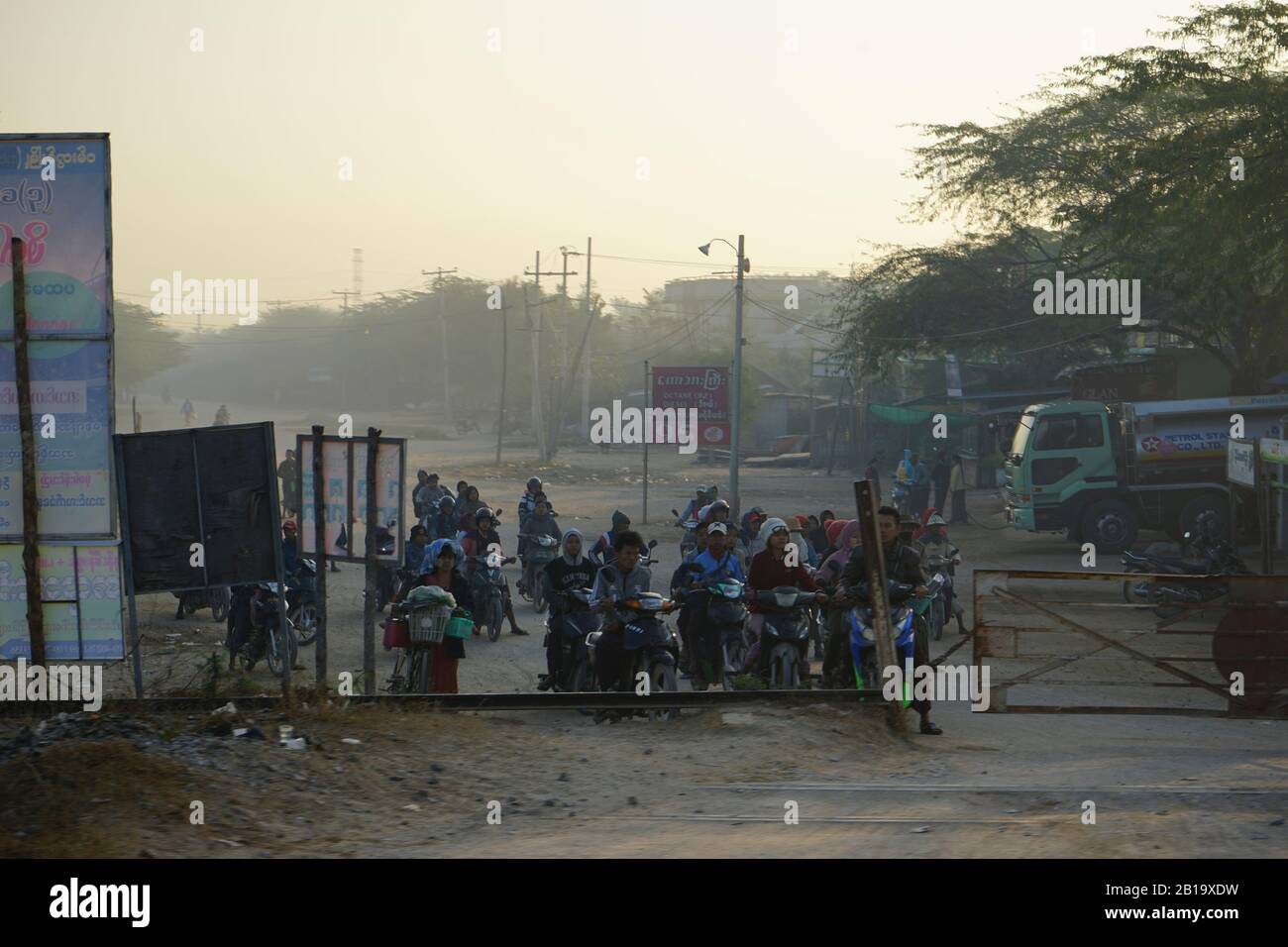 Menschen auf Motorrädern warten vor Bahnschranke, Zugstrecke von Yangon nach Mandalay, Myanmar Stockfoto