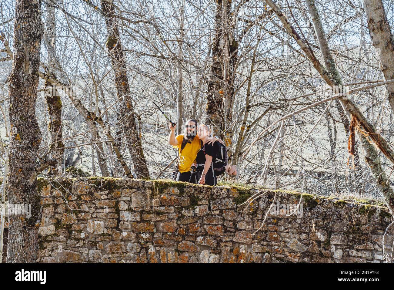 Ein paar bärtige Männer und Frauen mit roten Haaren auf einer Steinbrücke sehen die Landschaft in einer Umgebung mit Bäumen Stockfoto