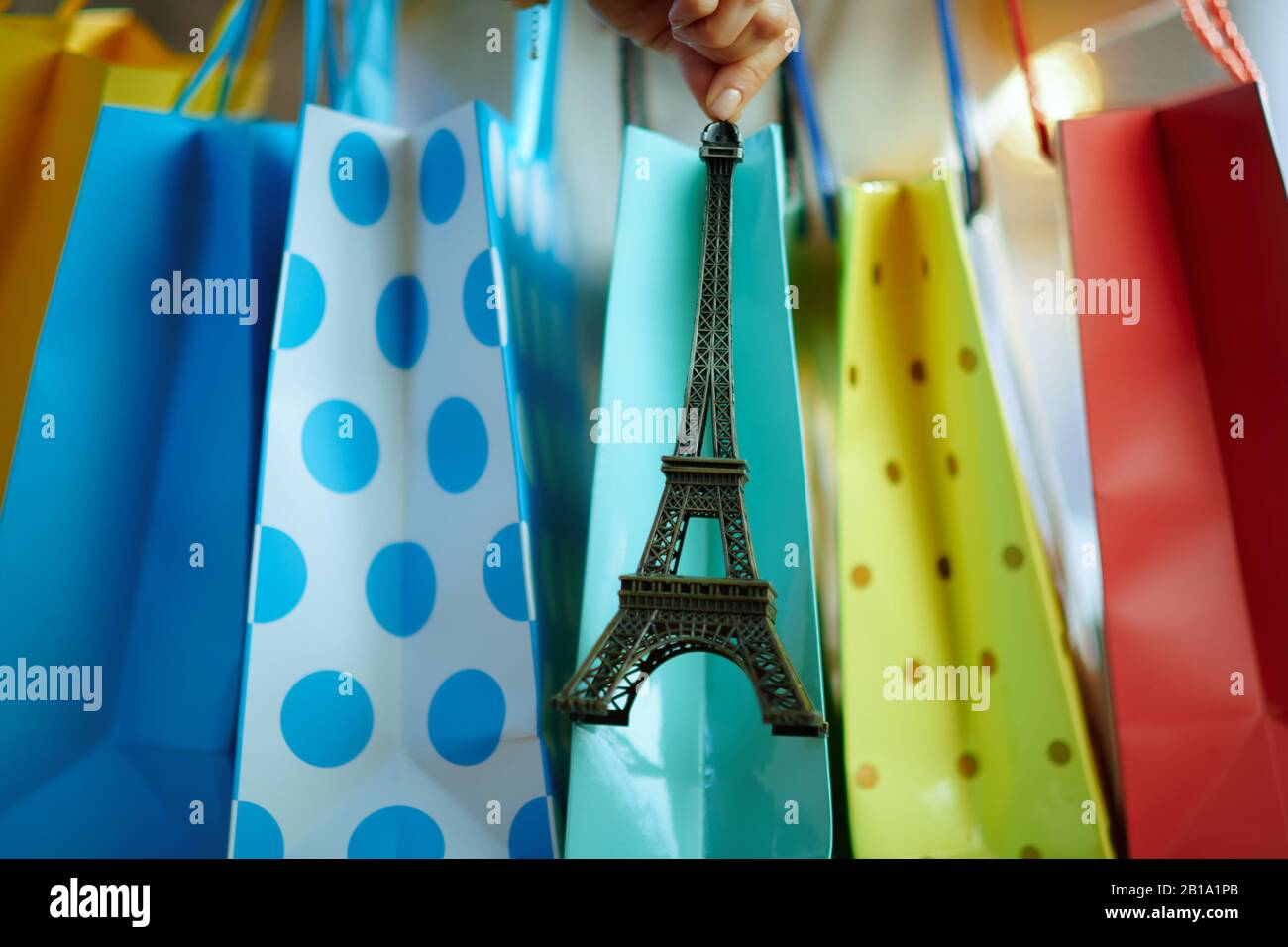 Nahaufnahme der Frau in der Nähe von bunten Einkaufstaschen, die ein Souvenir des Eiffelturms zeigen. Stockfoto