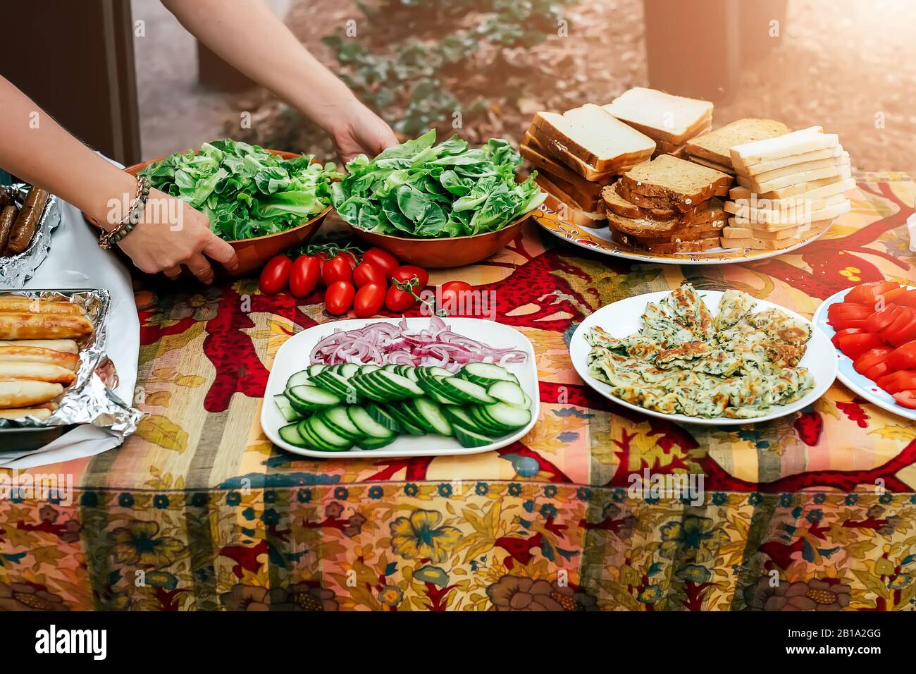 Die Leute bereiten Speisen für die Party zu, servieren Grillwürste grünen Salat, Vegien und Brot auf dem Tisch. Öffentlicher Grillplatz in Australien. Picknick im Park. Stockfoto