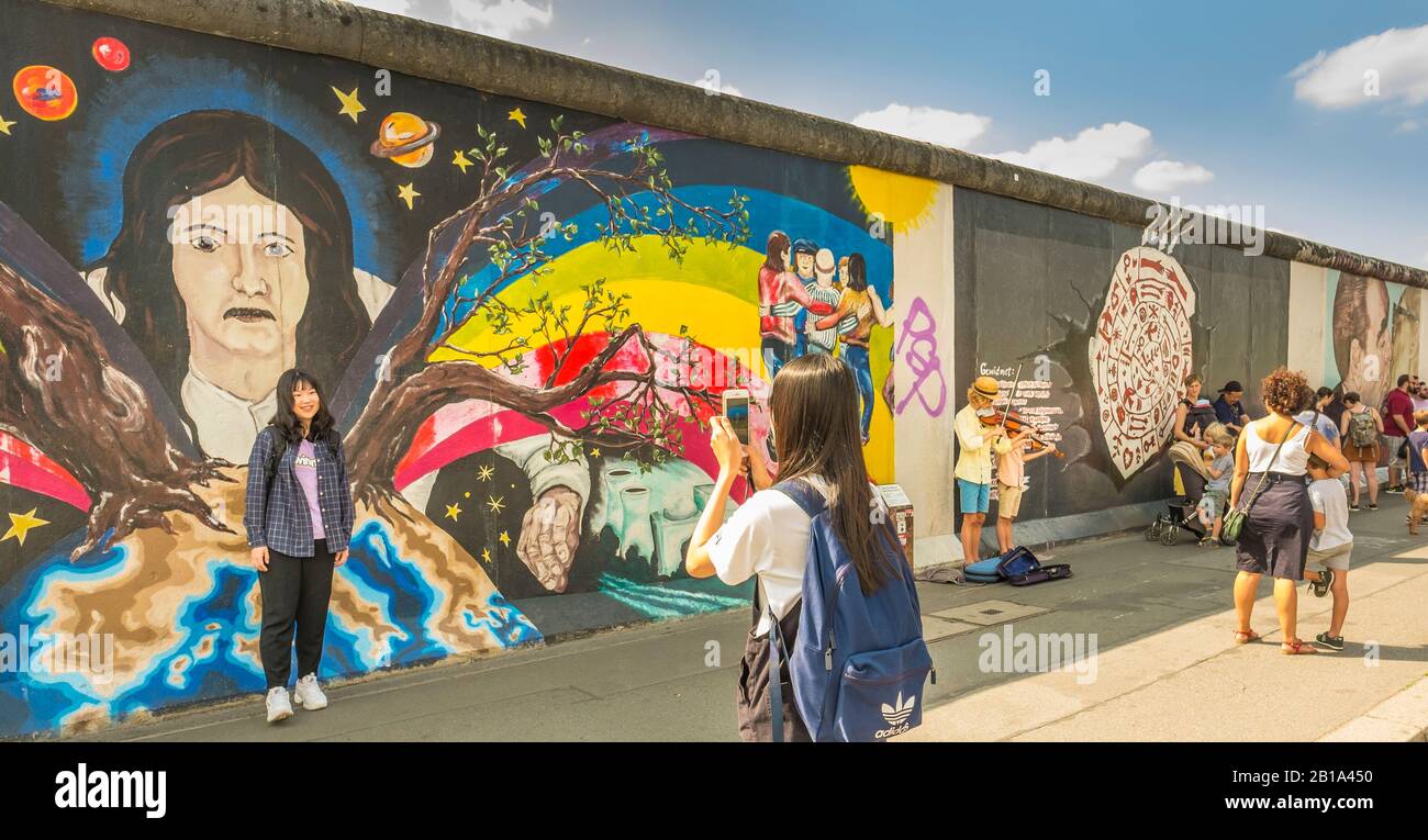 Junge asiatin posiert vor Wandbild an der Ostseitengalerie Stockfoto