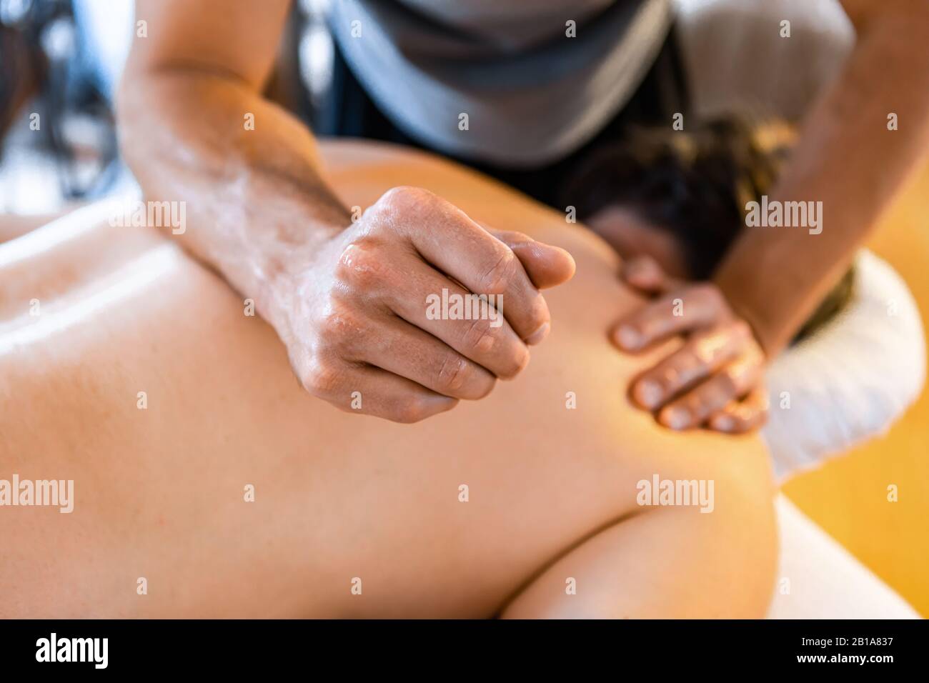 Ein starker männlicher Massagetherapeut, der einem Mann eine tiefe Gewebemassage gibt. Konzepte der Physiotherapie und der Chiropraktik Stockfoto