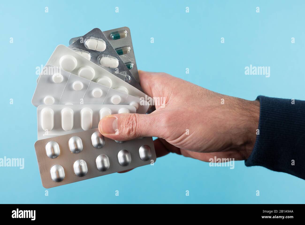 Nahaufnahme von Handpackungen mit Blisterpackungen von Tabletten und Kapseln vor blauem Hintergrund Stockfoto