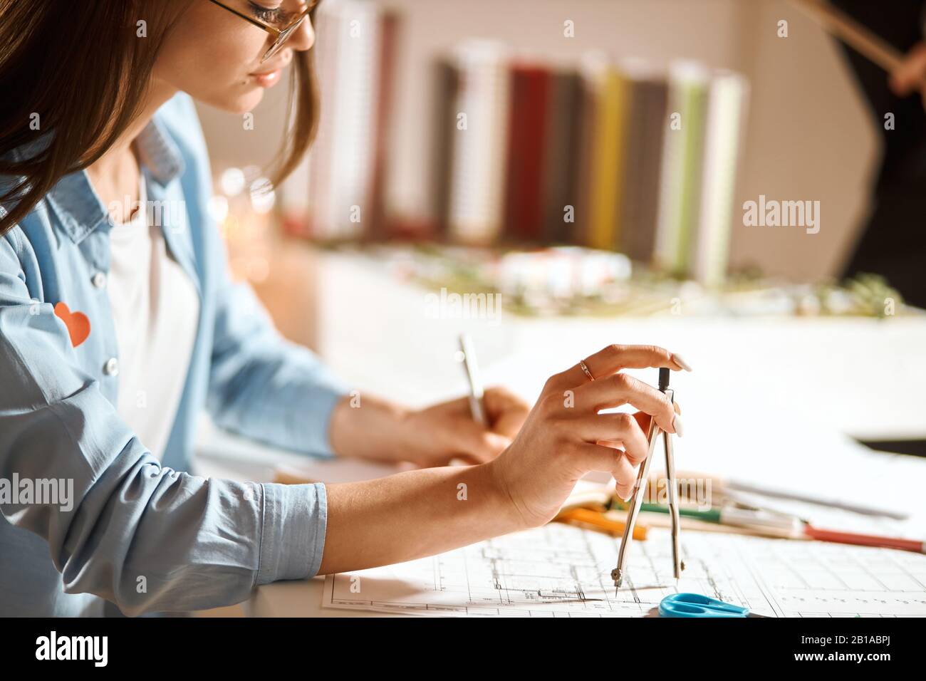 Junger, junger, schöner Architekt, der mit einem Paar Kompasse einen Kreis bildet. Nahaufnahme des Fotos mit Seitenansicht. Zugeschnittenes Foto Stockfoto