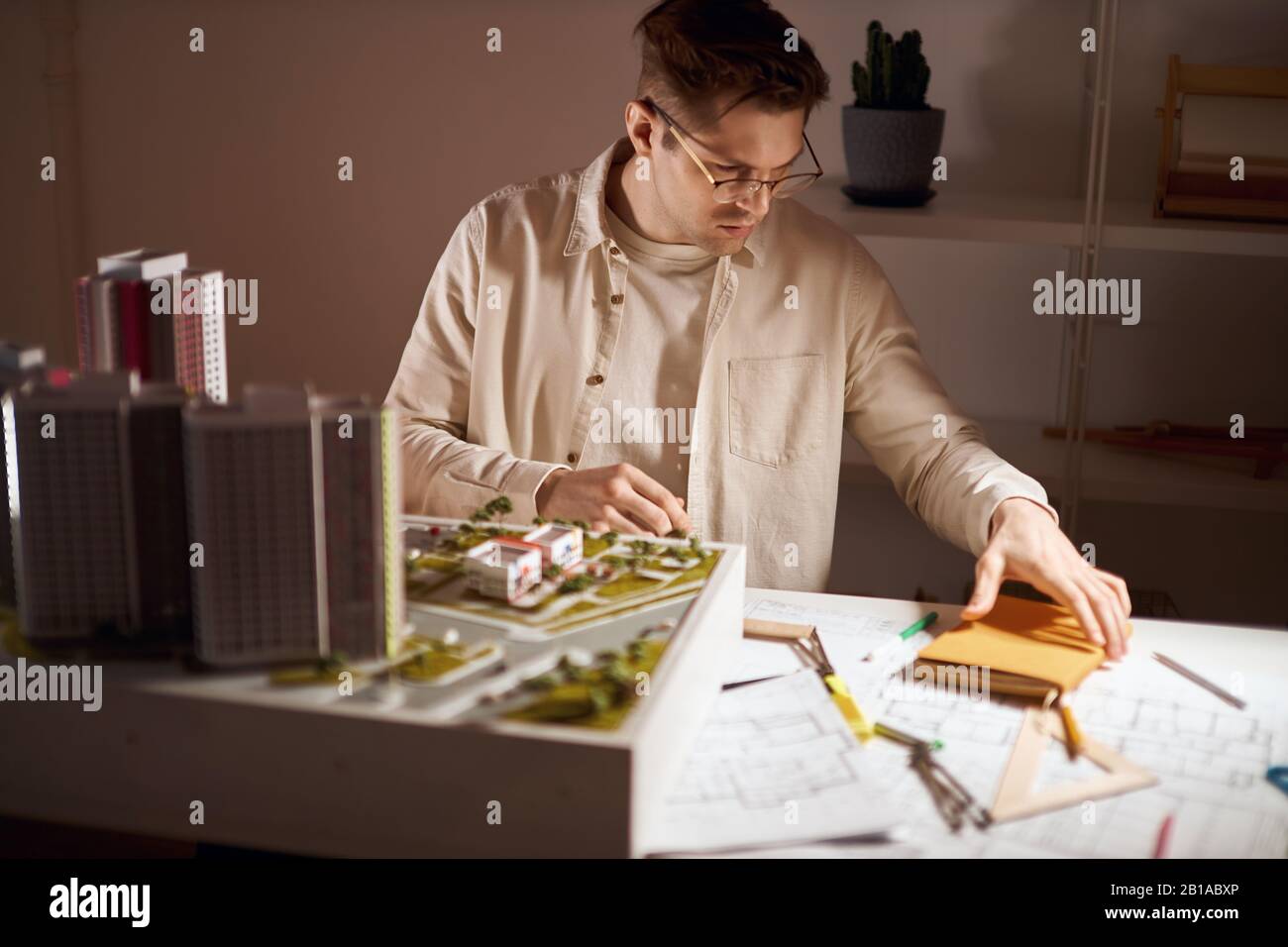 Junger gutaussehender Mann in Brille und weißem Hemd, der sein gelbes Notizbuch nimmt, um einige Notizen zu machen, Nahaufnahme Foto. Kerl, der nützliche Informationen schreiben wird Stockfoto