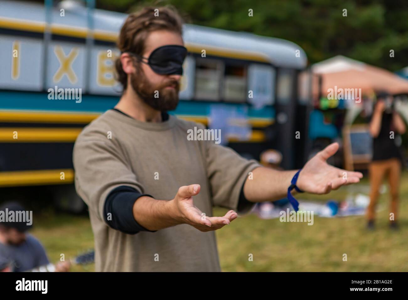 Ein selektiver Fokusschuss eines Mannes, der eine Augenbinde trägt und die Hände während spiritueller Übungen auf einem multikulturellen Festival aushält. Ajna Chakra Training Stockfoto