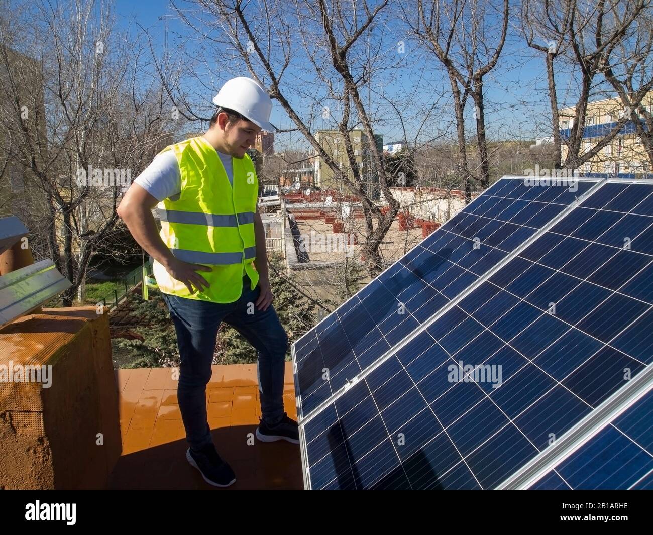 Kaukasisch attraktiver junger Techniker mit Blick auf die Sonnenkollektoren. Alternative Stromquelle, nachhaltige Ressourcenkonzeption. Stockfoto