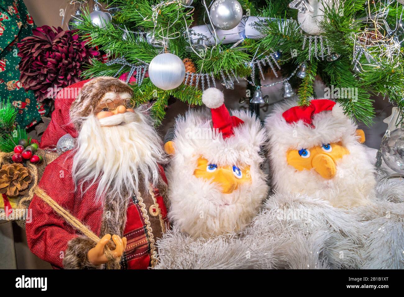 Weihnachtsmann-Verzierungen unten an einem Weihnachtsbaum im Inneren, der traditionell mit tönenden Lichtern, Tinsel und Baubeln dekoriert ist. Stockfoto