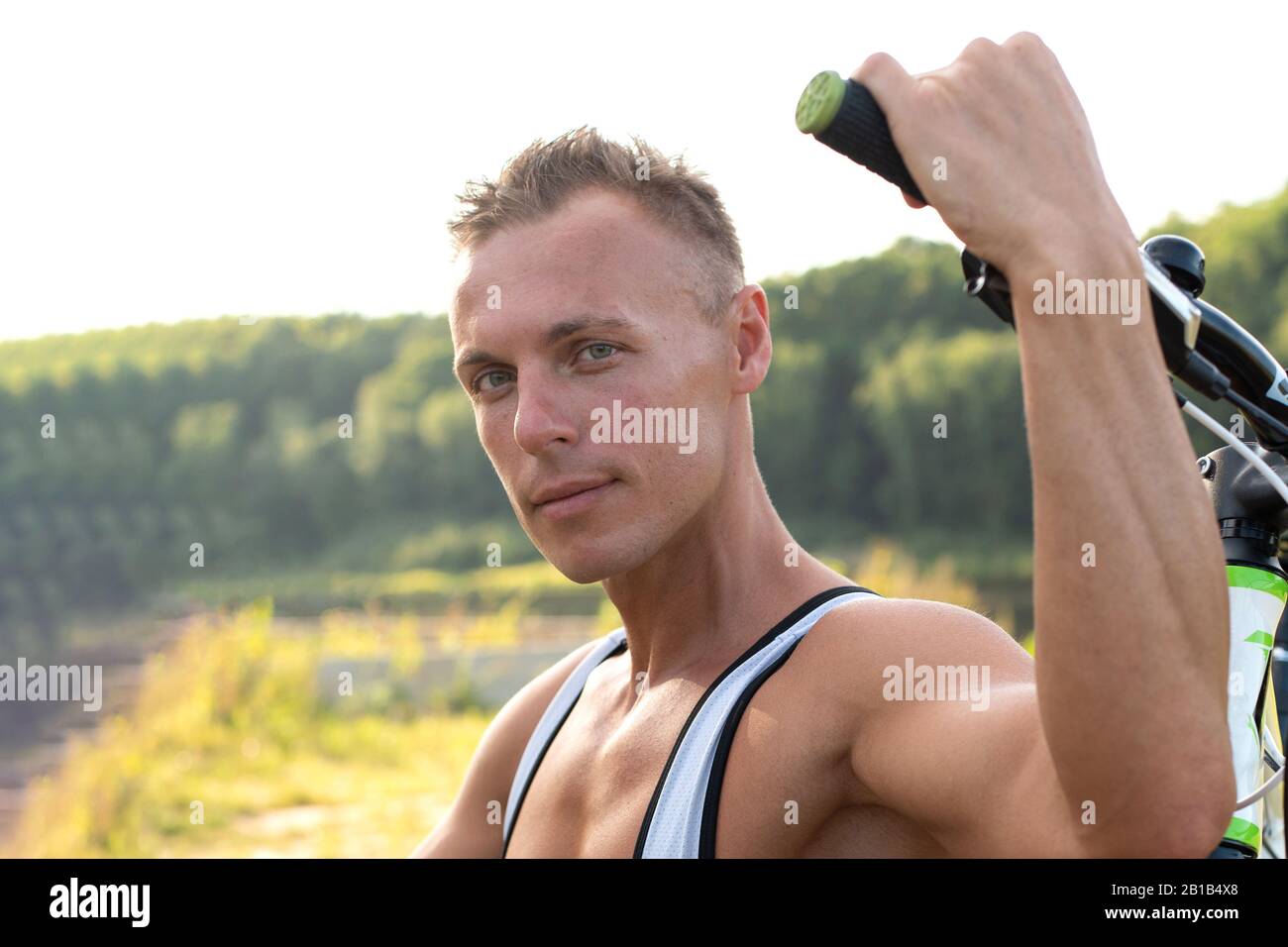 Ein Mann mit einem Fahrrad in der Natur. Im Feld, im Sommer. Stockfoto