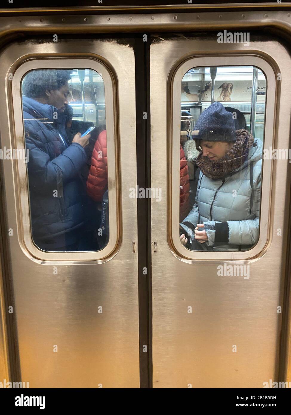 U-Bahn-Zugfahrer halten während der immer überfüllten morgendlichen Hauptverkehrszeit in Zügen, die von Brooklyn nach Manhattan fahren, mit ihren Handys besetzt. Stockfoto