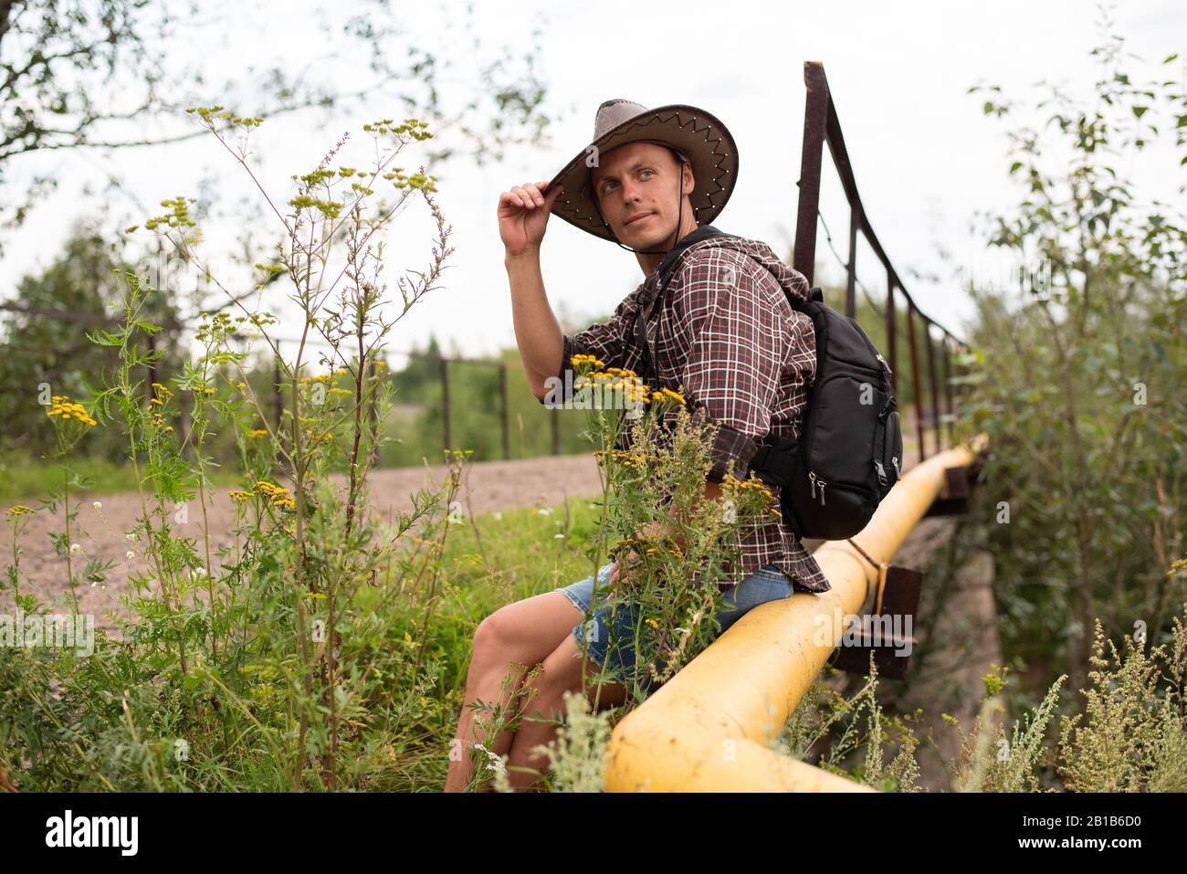 Ein Mann in einem Cowboyhut sitzt auf einer Gasleitung. Stockfoto