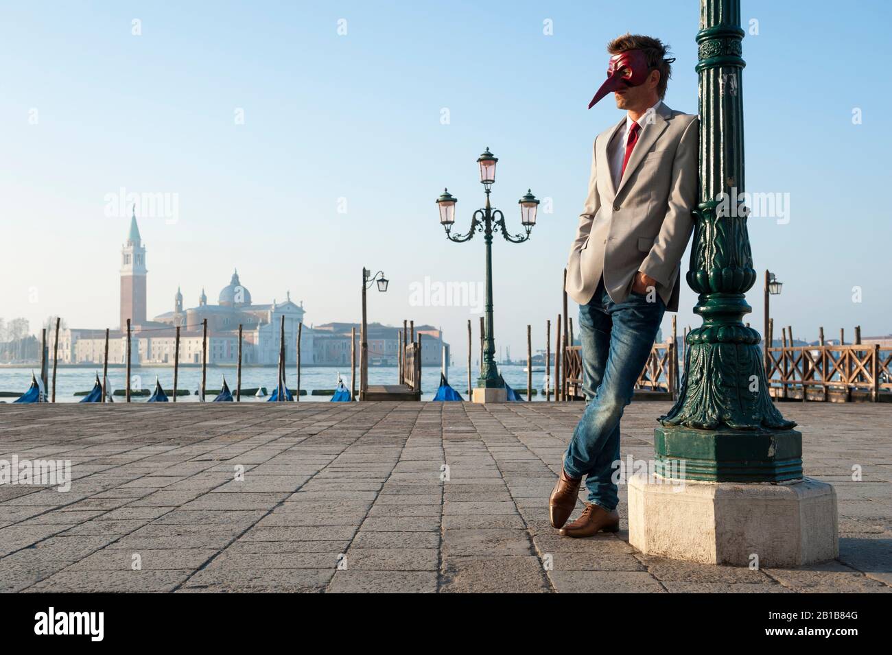 Mann, der eine Karnevalsmaske trägt, steht draußen auf einem platz in Venedig, Italien Stockfoto