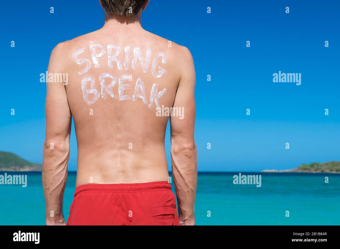 Nicht erkennbarer Federbrecher mit Spring Break in Sonnenschutzanzeige auf dem Rücken, der über den tropischen Inselhorizont blickt Stockfoto