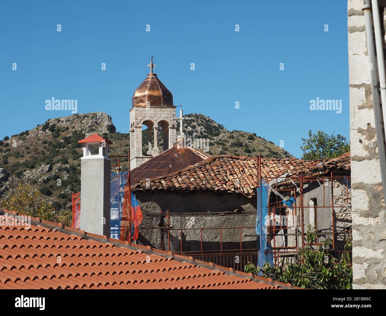 Fliesen- und Kirchturm mit Kupferkuppel und Kreuz in Dimitrana, Arcadia, Peloponnes, Griechenland, gegen einen blauen Himmel. Stockfoto