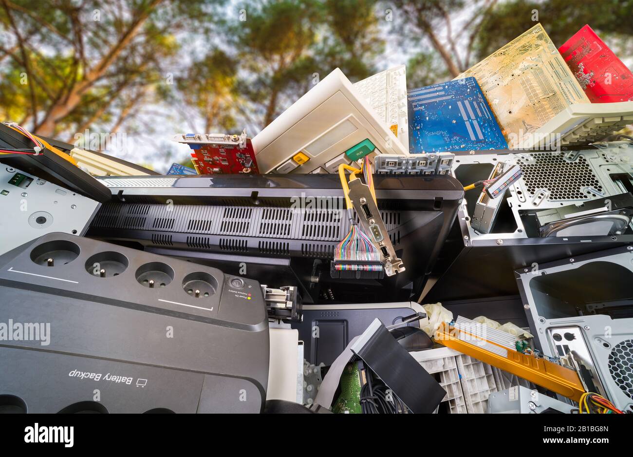 Details zu Elektronikschrott. Hardwarekomponenten des Computers, die unter Bäumen gehaufen sind. Nahaufnahme von gebrauchten PC-Teilen aus Kunststoff oder Metall in der Natur. Umweltfreundlich, CO2-Bilanz. Stockfoto