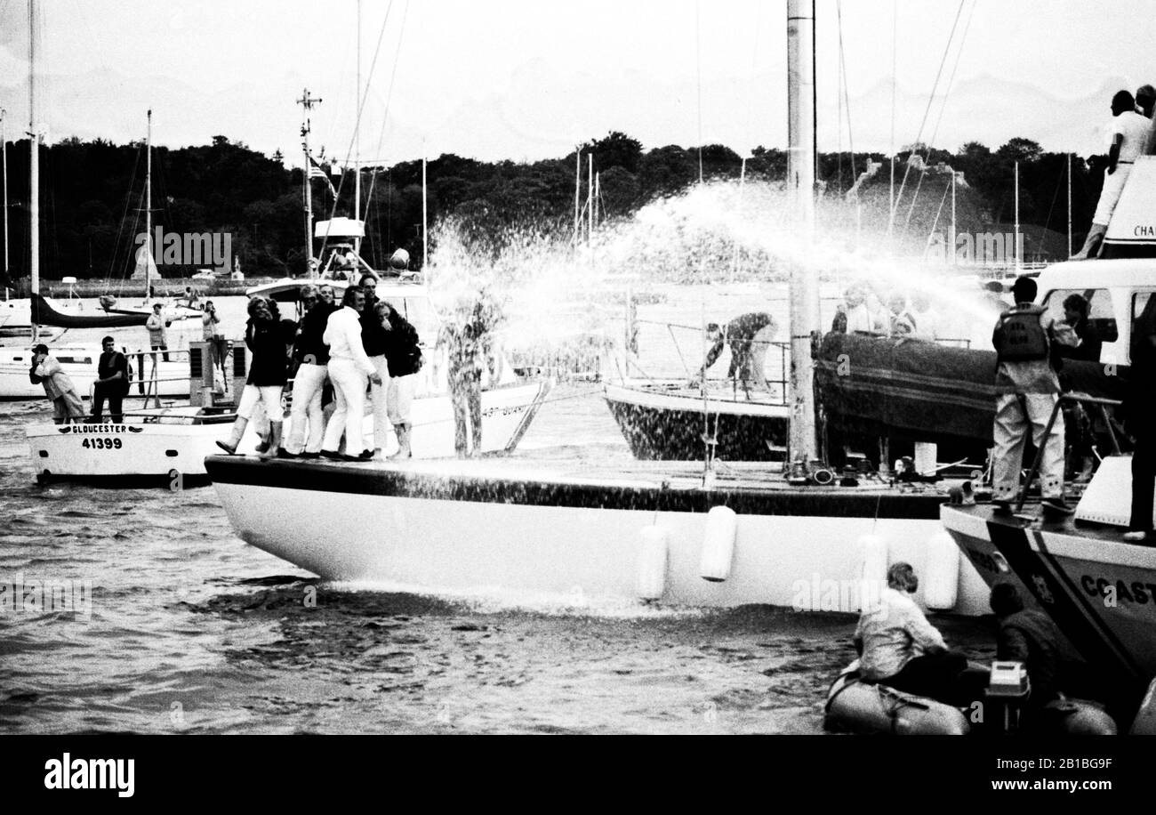 AJAXNETPHOTO. 1980. NEWPORT, RHODE ISLAND, USA. - AMERICA'S CUP - DIE MANNSCHAFT DES 12M ENTERPRISE ERHÄLT AM ENDE EINES TAGES EINEN EINSTAND VON EINEM KÜSTENWACHENSCHNEIDER IM HAFEN VON NEWPORT. FOTO: JONATHAN EASTLAND / AJAX REF:800926 21A Stockfoto